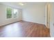 Bare bedroom with wood-look floors, neutral walls and trim, and double windows facing the outdoors at 7214 W Reformatory Rd, Fortville, IN 46040