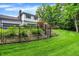 Beautifully landscaped backyard with a black metal fence, lush greenery, and a charming view of the home and deck at 7255 Haverhill Ct, Indianapolis, IN 46250
