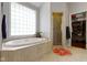 Bright bathroom with a large tub, glass block window, walk-in shower, and tile flooring at 7744 Preservation Dr, Indianapolis, IN 46278