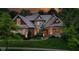 Stunning brick home illuminated at twilight showcasing its landscaping and design at 7744 Preservation Dr, Indianapolis, IN 46278