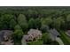 An aerial view showcasing the front facade and wooded surroundings of the brick home at 7744 Preservation Dr, Indianapolis, IN 46278