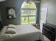 Relaxing bedroom featuring a bed with a white comforter, a guitar, and a window overlooking the front yard at 7838 Chesapeake E Dr, Indianapolis, IN 46236