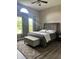 Stylish bedroom features a gray upholstered bed, a bench, and a large window with decorative curtains at 7838 Chesapeake E Dr, Indianapolis, IN 46236