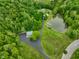 A stunning aerial view of a property with a private pond surrounded by lush greenery and mature trees at 8000 Mcwhorter Rd, Martinsville, IN 46151