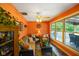 Bright living room with many windows, orange walls, ceiling fan and wicker furniture at 8000 Mcwhorter Rd, Martinsville, IN 46151