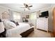 Bright bedroom featuring a ceiling fan, dresser with television, and comfortable queen bed near two windows at 9104 W Lone Beech Dr, Muncie, IN 47304