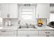 Well-lit kitchen sink area with white cabinetry and stylish decor at 9104 W Lone Beech Dr, Muncie, IN 47304