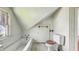 A bathroom under the eaves features a toilet, tub, and a small door with a towel rack at 102 N Whitcomb Ave, Indianapolis, IN 46224