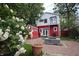 Landscaped backyard with stone firepit, brick walkway, red shed, white roses and two-story home at 1156 Spruce St, Indianapolis, IN 46203