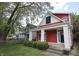 Charming red two-story home featuring a covered front porch with white columns and manicured landscaping at 1156 Spruce St, Indianapolis, IN 46203