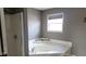 Bathroom featuring corner bathtub with shower and window and neutral gray walls at 11754 Hamble Dr, Indianapolis, IN 46235