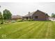 A well-maintained backyard with a manicured lawn, landscaped flowerbeds, and brick home, creating a serene outdoor space at 120 Wagon Trail, Mooresville, IN 46158