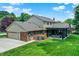 Exterior of a home featuring brick accents, attached garage, covered patio, and a well-manicured lawn at 1219 Driftwood Dr, Carmel, IN 46033