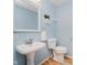 Charming powder room with pedestal sink, a decorative mirror, and soft blue walls at 13896 Fernleaf Way, Carmel, IN 46033