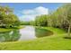 Scenic view of a pond surrounded by lush greenery and trees under a bright blue sky at 13896 Fernleaf Way, Carmel, IN 46033