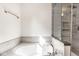 Modern bathtub with grey tile surround, glass shower door, and chrome fixtures at 197 Ceejay Dr, Greenwood, IN 46142