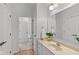 Bathroom vanity with beige counter, white cabinets, large mirror, chrome fixtures, and doorway to additional bathroom area at 2075 Rhettsbury St, Carmel, IN 46032
