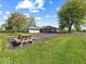 Exterior of a single-story home and detached garage surrounded by a spacious yard, picnic table, and paved driveway at 2233 S Miller Ave, Shelbyville, IN 46176