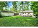 The house has a charming backyard with lush green grass, a detached garage, and mature trees at 332 Campus Ln, Indianapolis, IN 46219