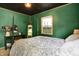 Unique bedroom with dark green walls and a four-poster bed with soft, neutral bedding at 332 Campus Ln, Indianapolis, IN 46219