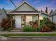 Charming home featuring a covered front porch surrounded by vibrant landscaping and red roses at 334 E Pennsylvania St, Shelbyville, IN 46176