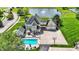 Aerial view showcases a backyard with a pool, basketball court, and peaceful pond with a fountain at 3398 Nottinghill Blvd, Plainfield, IN 46168