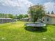 Large backyard featuring a trampoline, well maintained lawn, fire pit, and mature trees at 3538 Whalen Ave, Indianapolis, IN 46227