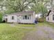Quaint one-story home with a gravel driveway and mature trees providing ample shade at 4415 N Longworth Ave, Indianapolis, IN 46226