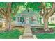 Charming blue home featuring a welcoming front porch, surrounded by mature trees and manicured landscaping at 4621 E 17Th St, Indianapolis, IN 46218