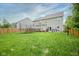 Large, grassy backyard showcasing a trampoline, wooden deck, and fencing for privacy at 5374 John Quincy Adams Ct, Plainfield, IN 46168