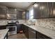 Modern kitchen with stainless steel appliances, granite countertops, and dark cabinets with stylish backsplash at 5374 John Quincy Adams Ct, Plainfield, IN 46168