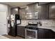 Modern kitchen featuring stainless steel appliances, dark cabinets, and granite countertops with modern backsplash at 5374 John Quincy Adams Ct, Plainfield, IN 46168
