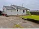 Quaint single-story home with a well-maintained lawn, driveway and neutral-colored siding under an overcast sky at 613 Anderson Rd, Anderson, IN 46017