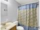 A compact bathroom featuring a vanity, toilet, and shower with a patterned curtain at 7061 Blankenship Ave, Indianapolis, IN 46217