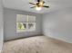 A bedroom with wall to wall carpet, a ceiling fan, and a window overlooking the front yard at 7061 Blankenship Ave, Indianapolis, IN 46217