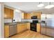 Updated kitchen featuring stainless steel appliances, granite countertops, natural wood cabinets, and laminate floors at 7061 Blankenship Ave, Indianapolis, IN 46217