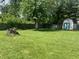Spacious backyard with a large tree stump, storage shed, and plenty of green grass at 7824 Hearthstone Way, Indianapolis, IN 46227