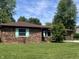 Brick home with beautiful lawn and landscaping features a brown roof and blue shutters at 7824 Hearthstone Way, Indianapolis, IN 46227