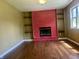 Spacious room with hardwood floors, a red brick fireplace, and built-in shelving at 7824 Hearthstone Way, Indianapolis, IN 46227