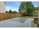 Well-maintained backyard with a basketball court, wood fence and lush green lawn for outdoor activities and relaxation at 7978 Park Meadows Dr, Brownsburg, IN 46112