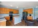 Open kitchen with wooden cabinetry, a center island, and black appliances at 8631 Belle Union Pl, Indianapolis, IN 46113