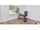 Bright room featuring a window, wood-look floors, and sleek black desk and chair at 9229 Crossing Dr, Fishers, IN 46037