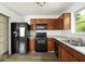 Functional kitchen featuring wood cabinetry, a complete black appliance set, and durable laminate flooring at 11821 Wapiti Way, Noblesville, IN 46060
