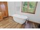 Relaxing bathroom featuring a soaking tub, wood floors, and a bright window at 12335 Old Stone Dr, Indianapolis, IN 46236