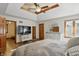 Bright main bedroom with tray ceiling, ceiling fan, wood floors, large windows, and an entertainment center at 12335 Old Stone Dr, Indianapolis, IN 46236