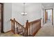 Bright staircase landing featuring wood railing, carpeted stairs, and an elegant chandelier at 12335 Old Stone Dr, Indianapolis, IN 46236
