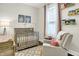 Calm Bedroom showcasing a crib, books on a shelf, comfy rocking chair and natural light from a window at 1333 Spann Ave, Indianapolis, IN 46203
