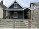 Charming home with dark siding, a quaint front porch, and a decorative fence adds to its curb appeal at 1518 S Talbott St, Indianapolis, IN 46225
