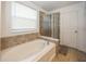 Bright bathroom features a soaking tub, glass-enclosed shower, and tiled surround at 15710 Chapel Park E Dr, Noblesville, IN 46060