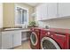 Modern laundry room featuring a sink, cabinetry, counter space, and updated red washer and dryer units at 16502 Grand Cypress Dr, Noblesville, IN 46060